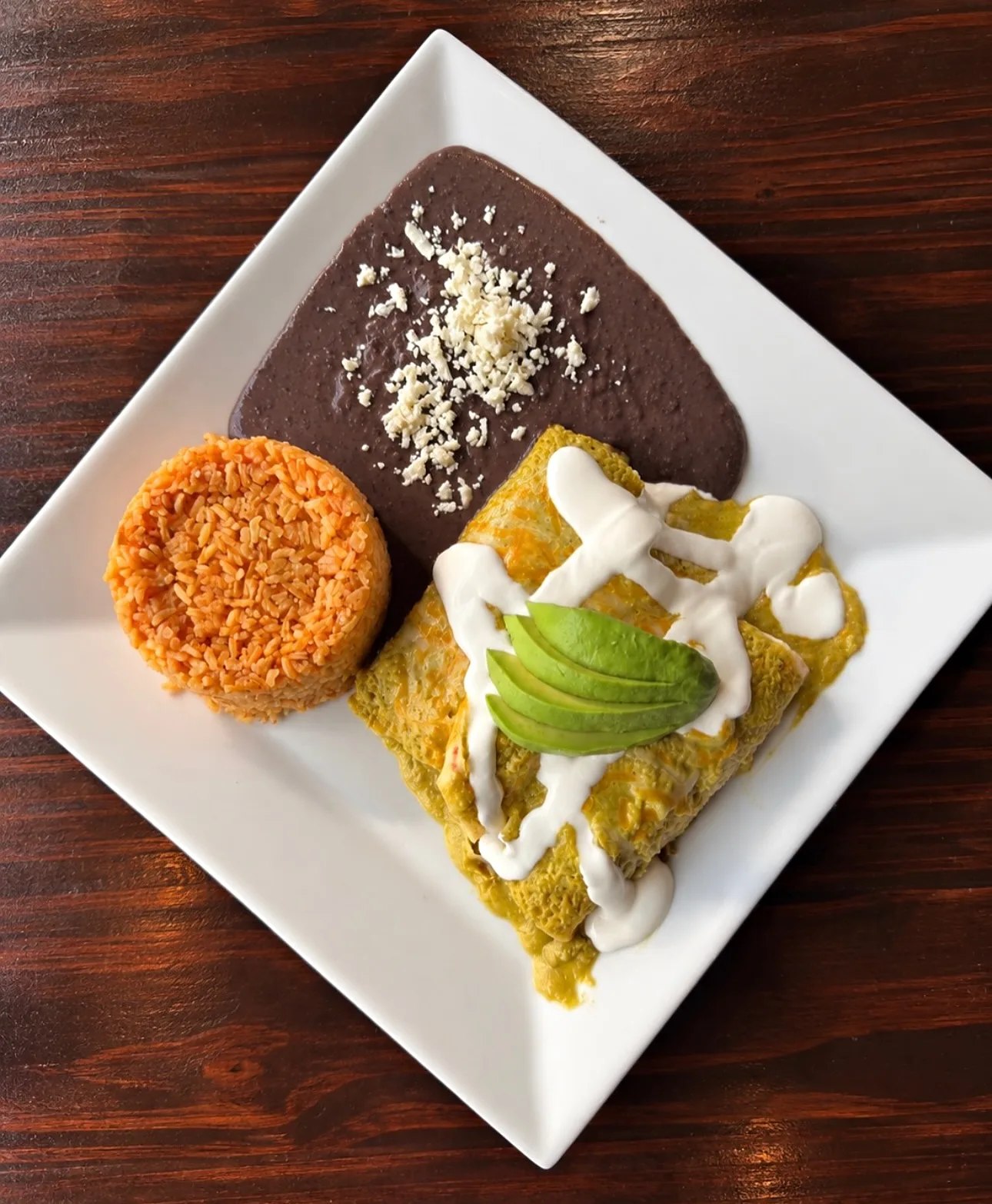 Enchiladas verdes with crema, avocado, rice and black beans